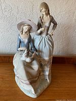 Front view of the Lladró porcelain sculpture featuring two standing and seated women on a common base