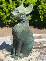 Front right angled view of bronze cat figurine showing posture and patina
