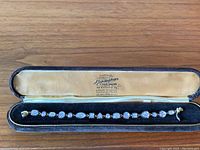 Photo of the antique silver bracelet with gold overlay and clear gemstones in original box showing overall appearance and maker's mark on inside lid.