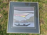 Full view of the framed Roy Vickers print showing the canoe, figures, mountains, and sky.