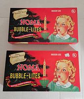 Two boxed Noma Nostalgia Series Bubble Lites with original packaging and front illustration of child and candle Bubble Lite.