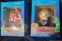 Both Rudolph hand-blown glass ornaments in original branded packaging boxes.