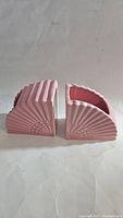 Pair of pink vintage pottery planters shaped like fans, shown from side to highlight the fan ribs and shape.