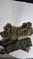 Pair of WWII US M1 Garand ammo belts laid flat, showing front pouch details and metal snaps