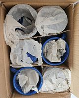 Set of 6 blue speckled enamelware mugs packed in a cardboard box with each mug wrapped in tissue paper.