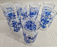 Set of eight clear vintage glasses with blue floral vine pattern, arranged closely.