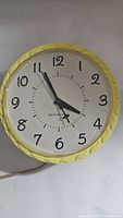Full view of vintage General Electric wall clock with yellow frame and black numerals.