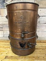 Full front view showing the copper still with embossed branding and inspection marks.