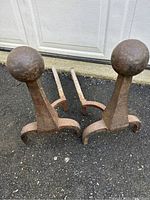 Pair of iron andirons viewed from front, showing hammered ball tops and claw-foot bases.