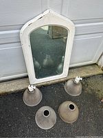 Photo of white framed antique mirror with arched top and four ribbed glass lamp shades placed on the ground