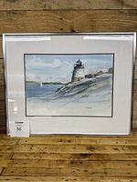 Full front view of watercolor painting in frame with white mat, depicting Castle Hill Light and coastal scenery.