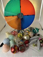 Photo showing the colorful working color wheel behind multiple assorted vintage and sugared glass Christmas ornaments in various shapes and colors.