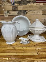 Photo showing all four ironstone serveware items grouped together on a wooden surface against a rustic wood wall backdrop.