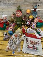 Wide view of all assorted pixies, elves, angels, and holiday ornaments on a wooden surface.