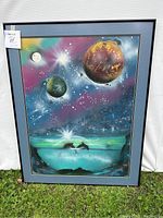 Front view of the framed colorful space-themed print with celestial bodies and dolphins, signed by Novu.