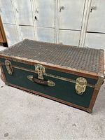 Front and top angled view of vintage green Concourse steamer trunk with copper edge and top covered with pennies.