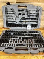 Full set inside gray hard plastic case showing upper section with wrenches, ratchets, and sockets and lower section with many sockets and extensions. Some sockets missing, rust on some parts.