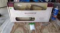Photo showing the Baldwin Prestige Series door handle and lock set in its original box, the door handle is visible through the cutout window on the front of the packaging.