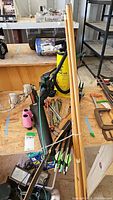 Full view of the lot laid on plywood showing bows, cue sticks, quiver with arrows, yellow air pump, and binoculars.
