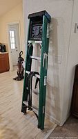 Green Husky 6ft ladder leaning against wall, displaying full ladder profile