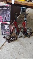 Two red and silver adjustable jack stands, metal chain, hydraulic bottle jack on the floor