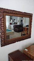 Front view of large wall mirror showing full carved wooden frame and reflective surface