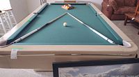 Full view of pool table playing surface with two cues and rack of balls