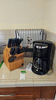 Wide view of Ronco knife block with knives, Brentwood coffee maker next to it, and metal dish rack in background.