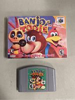 Photo of Banjo Tooie N64 video game cartridge and original box with front cover art showing characters Banjo, Kazooie, and others.