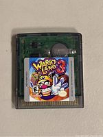 Game Boy Color cartridge for Wario Land 3 showing front label and clear casing revealing internal circuit board.