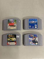 Four Nintendo 64 game cartridges laid out on a plain surface: San Francisco Rush 2049, Snowboard Kids 2, Beetle Adventure Racing, and Mario Kart 64. Some labels have small stickers and visible wear.