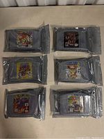 Six N64 game cartridges sealed in anti-static bags, showing labels for Mario Party 2, Mario Kart 64, Paper Mario, Donkey Kong 64, Conker's Bad Fur Day, and a second Mario Party 2 cartridge.