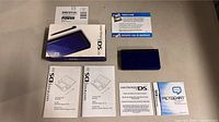 Full lot including Nintendo DS Lite blue handheld console, original box, instruction manuals, and registration cards.