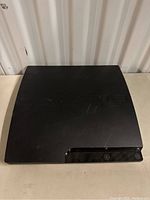 Photo of the black PlayStation 3 console with curved top and front buttons