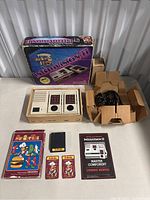 Full lot displayed: Intellivision II console, original box, power adapter and cables, BurgerTime game box with cartridge, two smaller cards, and manuals