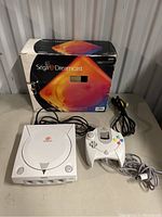 Console, controller, cables, power cord and original box arranged on table