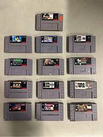 Top-down photo showing 12 SNES cartridges arranged in rows. Labels visible for title identification.