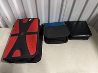 Three disc binders on a table: one with red and black design and Xbox 360 markings, two others black and blue and plain black.