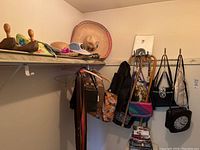 Wide view showing various ladies purses and handbags, hats on shelf, belts hanging, and two canes