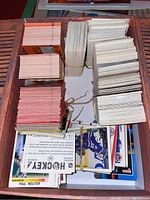 Wooden box filled with multiple stacks of assorted baseball and hockey cards, viewed from above.