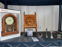 Full lot view showing all clocks and miniatures on a shelf against wallpapered wall.