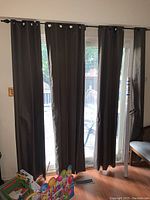 Eight dark gray polyester curtain panels hung on rods above a glass door.