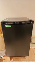 Front view of black Danby compact bar fridge with single door and logo at top center.