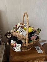 Wicker basket filled with various plush bears and animals bearing tags, including a prominent tag labeled '432 Ganz Bears'