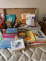 Wide shot showing the entire selection of pencil cases, crayons, markers, workbooks, and other teacher supplies arranged in a box.