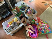 Overview of bin with Pee Wee Herman doll, plush duck, books, a party sign, and costume pieces scattered around