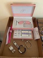 Overview of all items in the lot showing pink rimless sunglasses in box, Fondini interchangeable watch bands, and four individual watches of varying styles