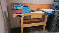 Front view of wooden work bench with two bags of Smart Sand Cubes on top, also showing adjustable shelf below.