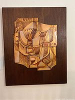 Full view of abstract glass art mounted on dark wood panel, showing overall shape and design.