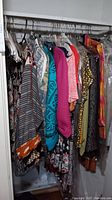 Photo showing a rack of ladies clothing items including striped tops, patterned sweaters, and colorful jackets and dresses.